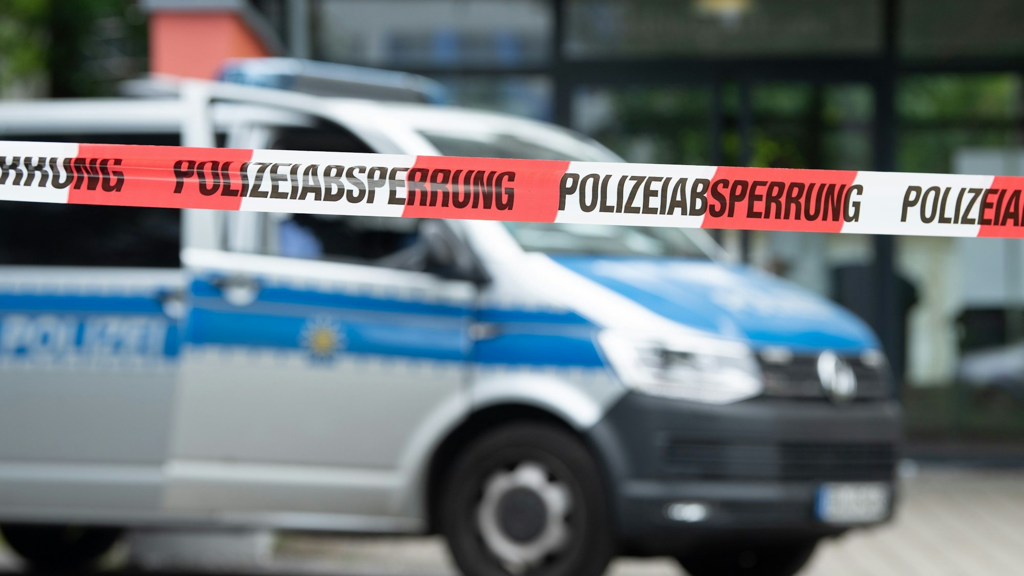 Ein Polizeiauto steht hinter einer Absperrung vor einem Studentenwohnheim.