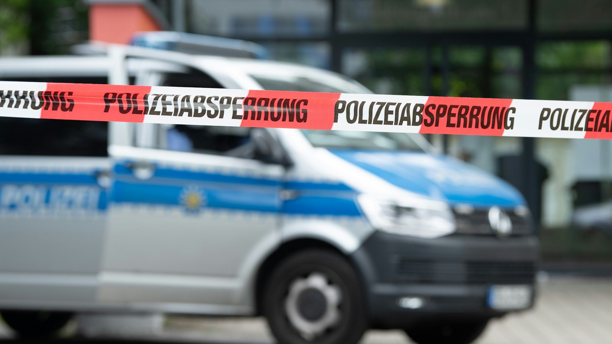 Ein Polizeiauto steht hinter einer Absperrung.