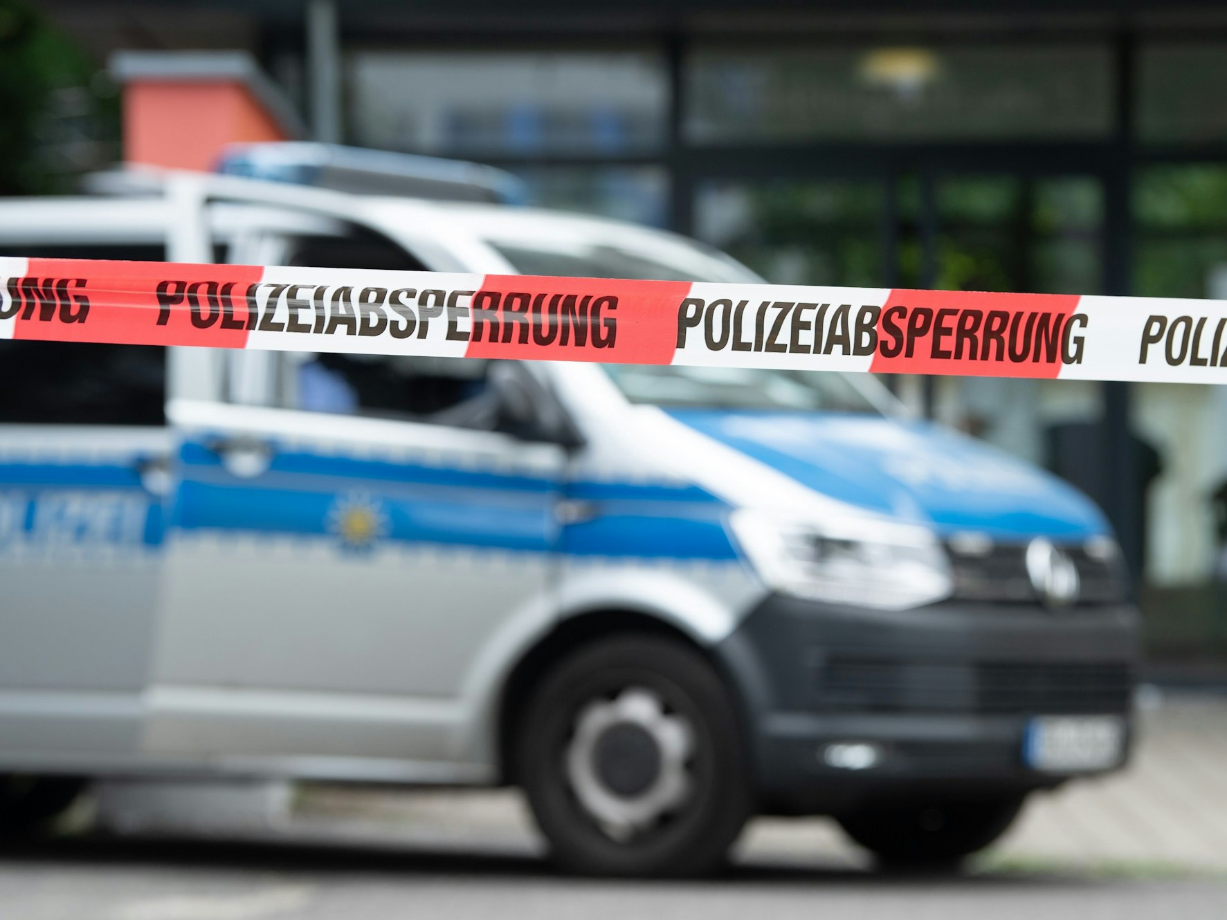 Ein Polizeiauto steht hinter einer Absperrung vor einem Studentenwohnheim.