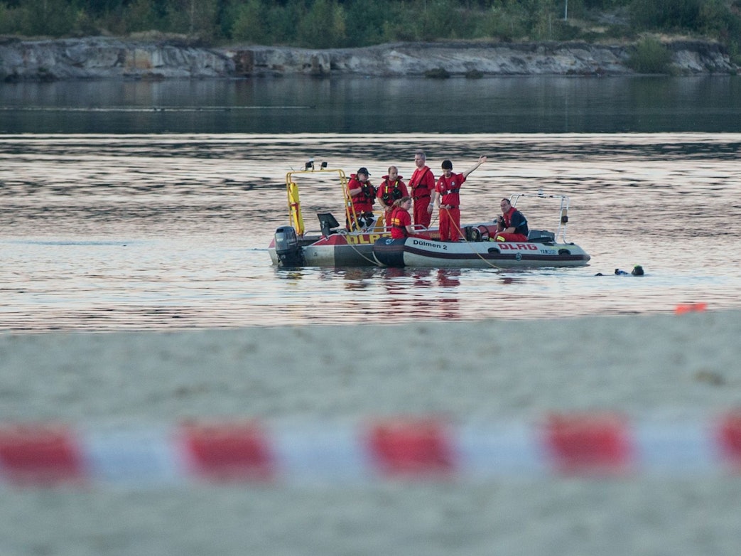 Einsatzkräfte der Feuerwehr und des DLRG fahren in Booten auf einem See.