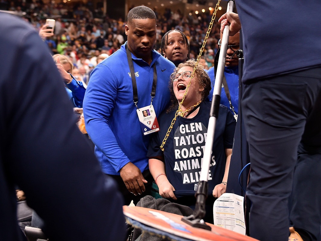 Mitarbeiter versuchen die Aktivistin von der Korbanlage zu trennen.