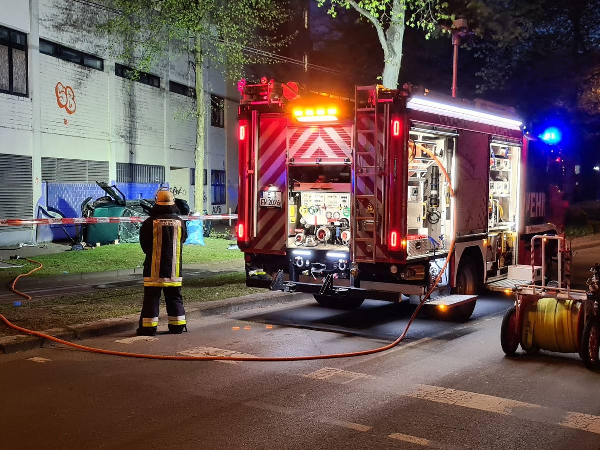 Ein Feuerwehrmann steht neben dem Wrack eines Autos. Zwei junge Männer sind am Ostersonntag in Essen mit einem Auto aus der obersten Etage eines Parkhauses gestürzt und ums Leben gekommen.