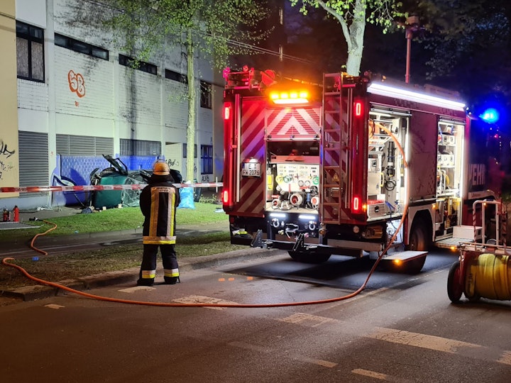 Ein Feuerwehrmann steht neben dem Wrack eines Autos. Zwei junge Männer sind am Ostersonntag in Essen mit einem Auto aus der obersten Etage eines Parkhauses gestürzt und ums Leben gekommen.