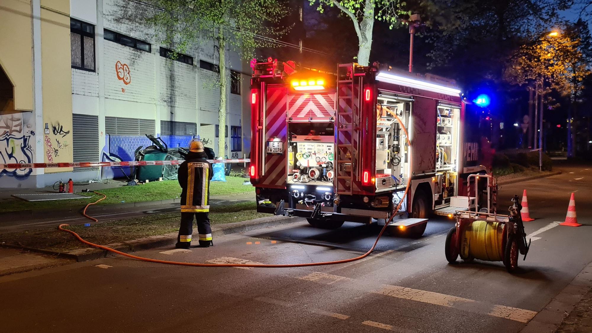 Ein Feuerwehrmann steht neben dem Wrack eines Autos. Zwei junge Männer sind am Ostersonntag in Essen mit einem Auto aus der obersten Etage eines Parkhauses gestürzt und ums Leben gekommen.