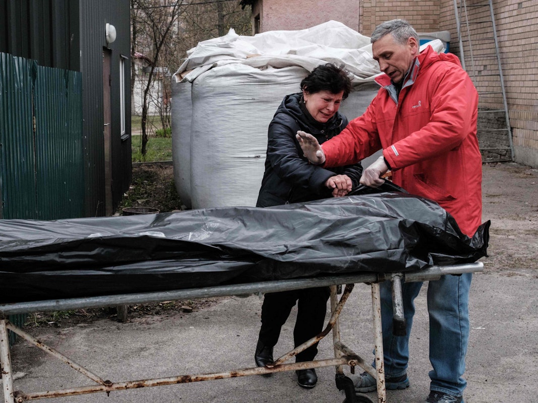 Ein ukrainisches Paar steht am 18. April vor dem Leichnam ihres Sohnes, der in Nähe von Butscha von ukrainischen Soldaten erschossen sein soll. Russlands Präsident Wladimir Putin hat jener Brigade, der massenhafte Tötungen in der Stadt vorgeworfen wird, nun einen Ehrentitel verliehen.