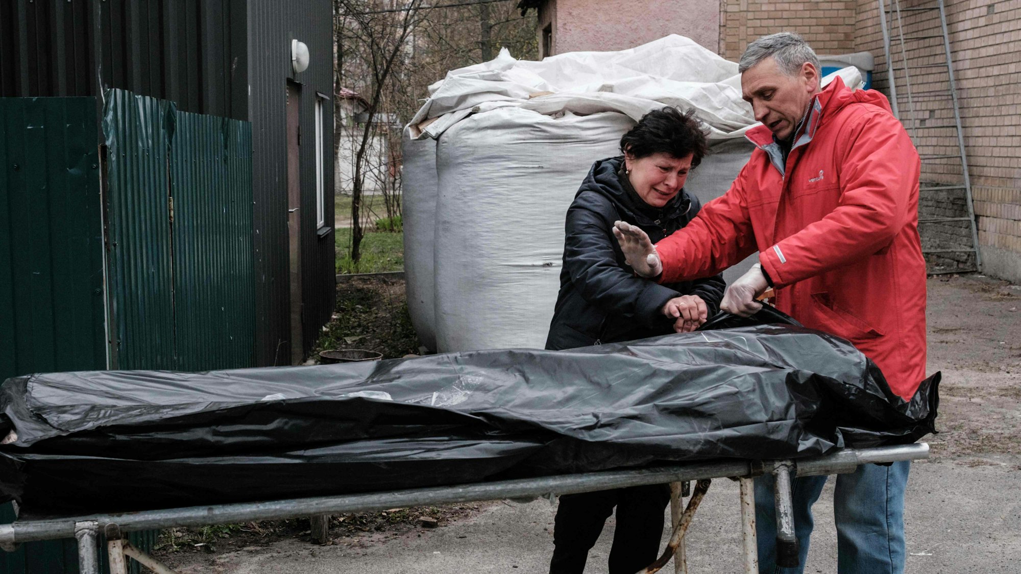 Ein ukrainisches Paar steht am 18. April vor dem Leichnam ihres Sohnes, der in Nähe von Butscha von ukrainischen Soldaten erschossen sein soll. Russlands Präsident Wladimir Putin hat jener Brigade, der massenhafte Tötungen in der Stadt vorgeworfen wird, nun einen Ehrentitel verliehen.
