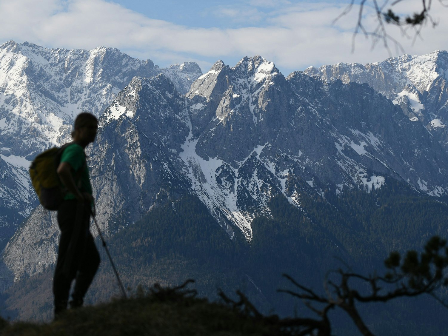 Ein Wanderer steht vor schneebedeckten Gipfeln.