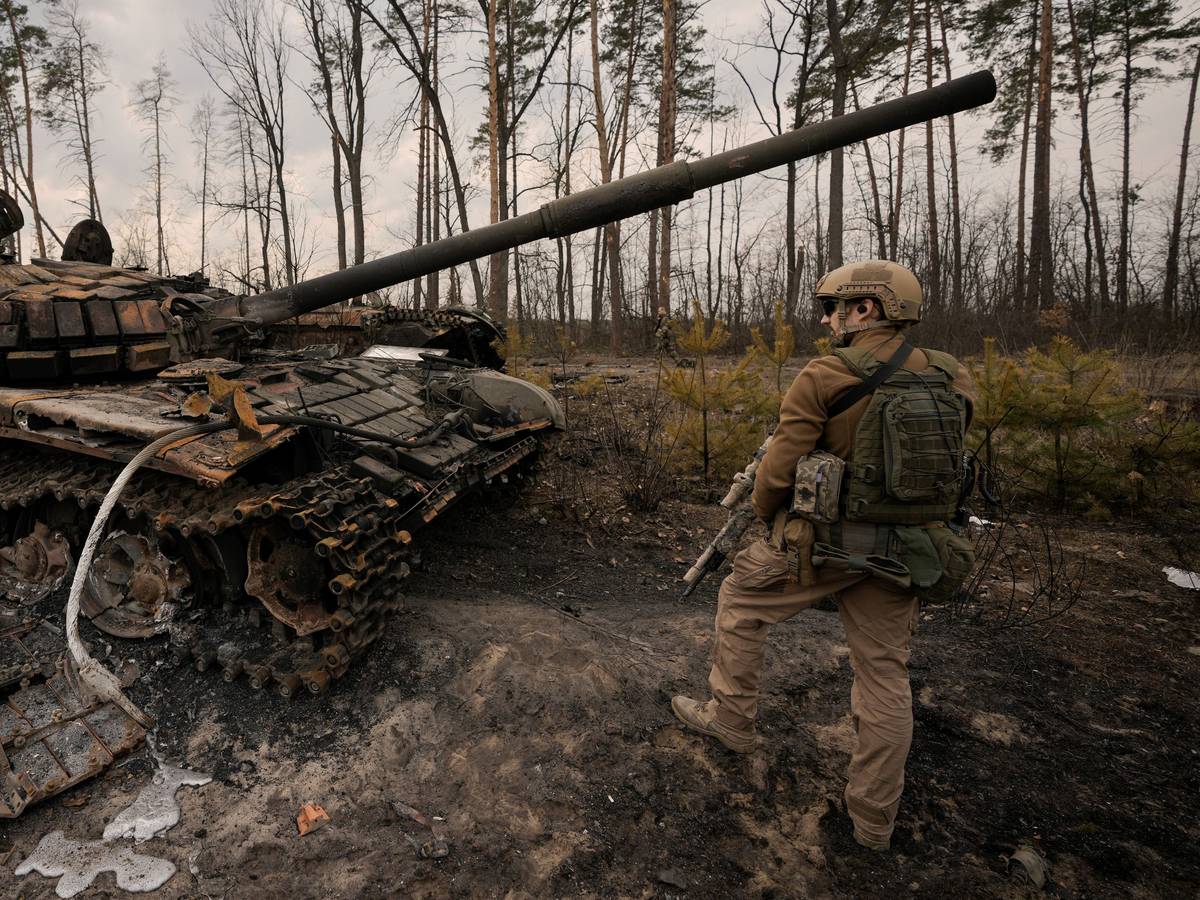 Ein ukrainischer Soldat steht am Stadtrand von Kyjiw neben einem zerstörten Panzer.