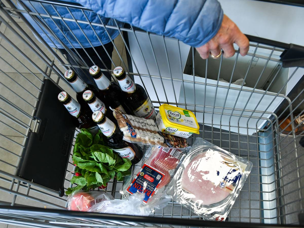 Ein Kunde hat Bier, Wurst, Margarine, Schinken und Salat in einen Einkaufswagen gelegt.