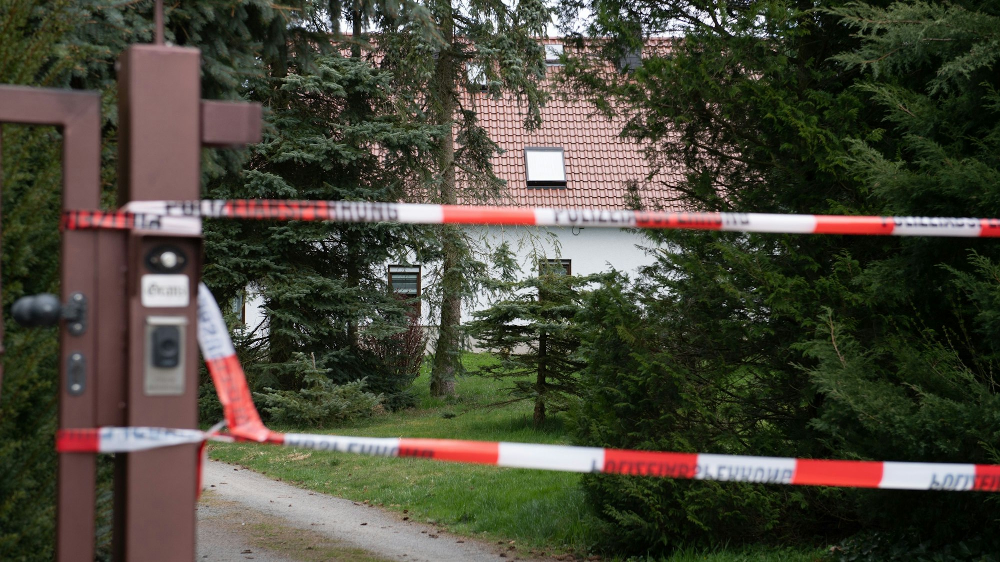 Ein Absperrband hängt an einer Einfahrt vor einem Wohnhaus. In dem Haus im Ortsteil Mittelbach wurden am späten Montagabend vier tote Menschen gefunden.