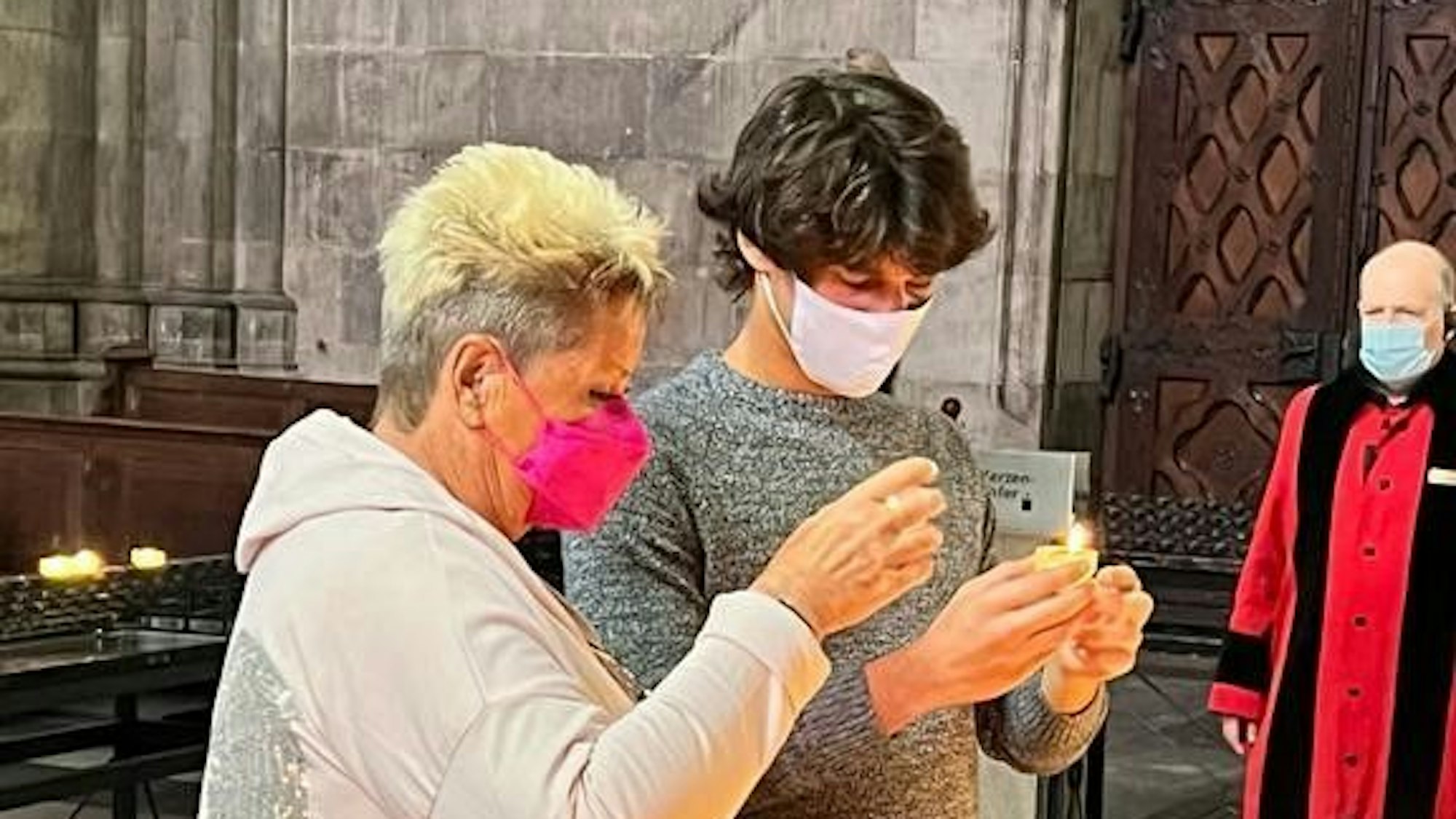 Marita und Emmanuel zünden eine Kerze im Kölner Dom an