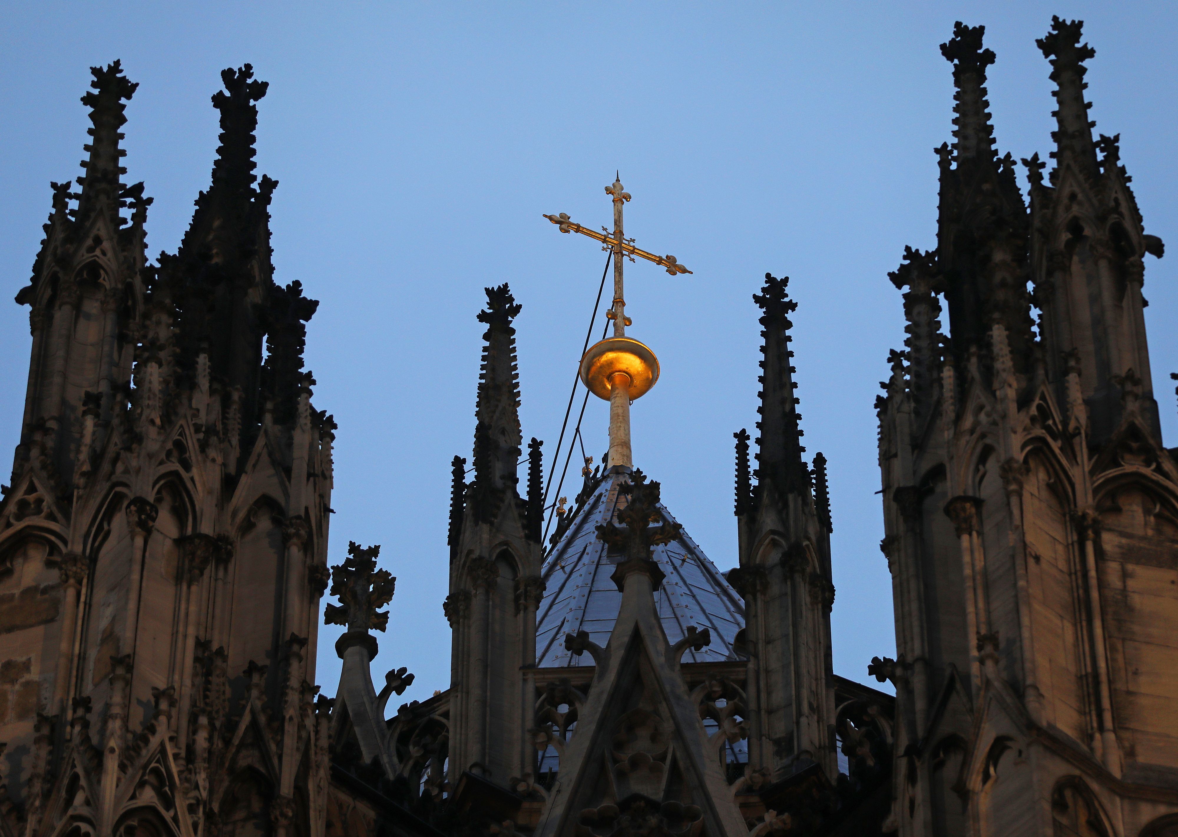 Ein Kreuz steht hinter dem Strebewerk am Dom.