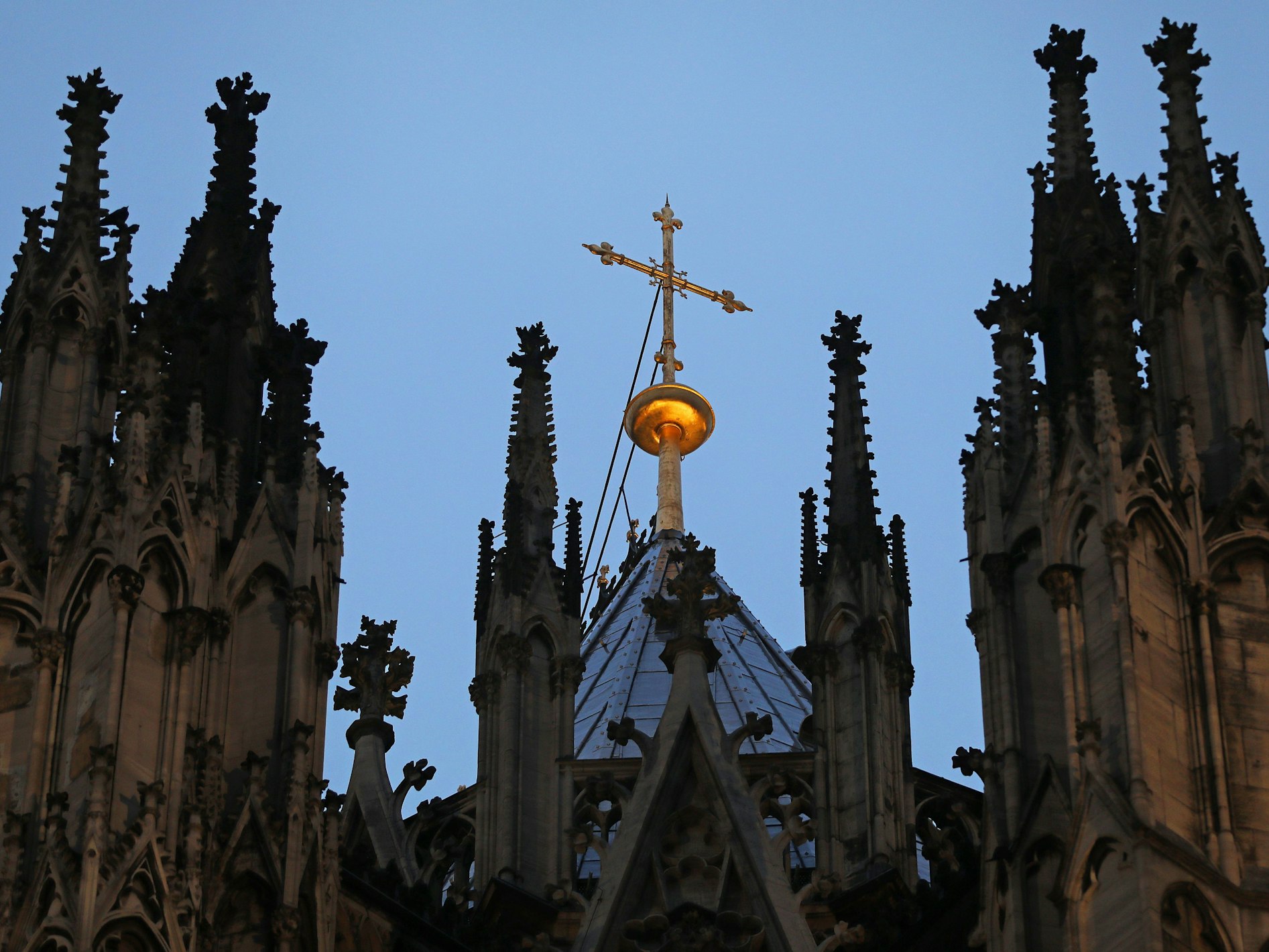 Ein Kreuz steht hinter dem Strebewerk am Dom.