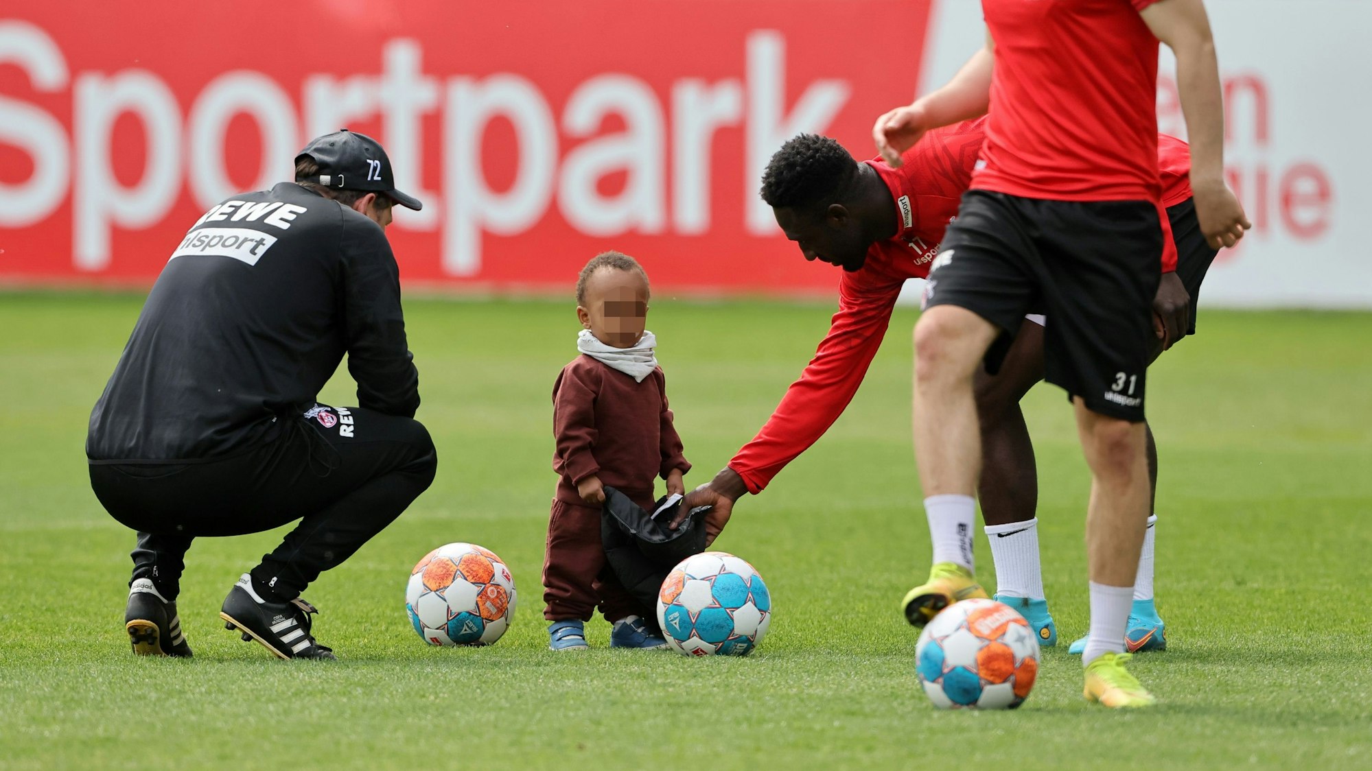 Kingsley Schindler spielt beim Mannschaftstraining des 1. FC Köln mit seinem Sohn.