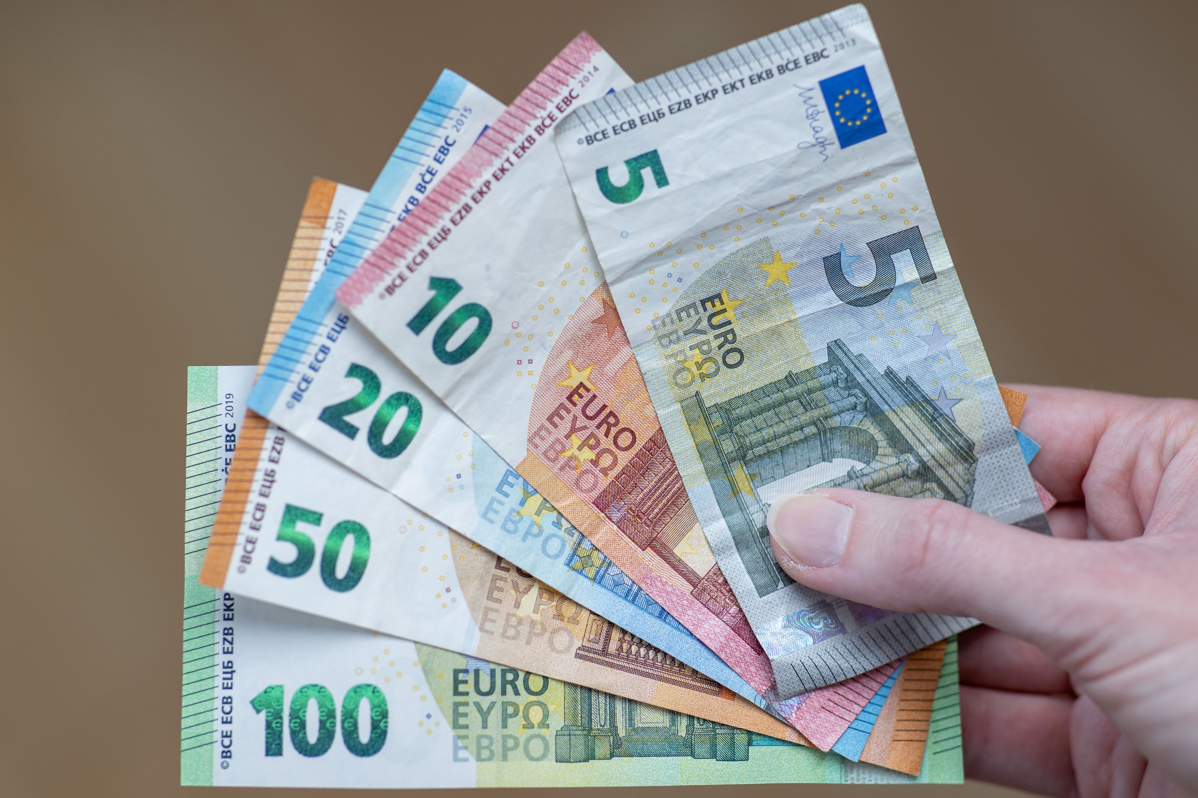 Eine Frau hält die Geldscheine 5 Euro, 10 Euro, 20 Euro, 50 Euro und 100 Euro in der Hand.