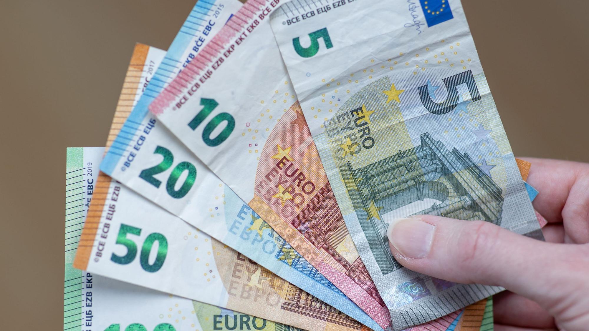 Eine Frau hält die Geldscheine 5 Euro, 10 Euro, 20 Euro, 50 Euro und 100 Euro in der Hand.