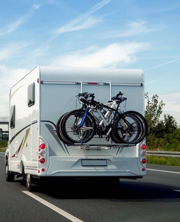 Hier zu sehen: Ein Wohnmobil, auf dem mehrere Fahrräder befestigt sind, fährt auf der Autobahn.