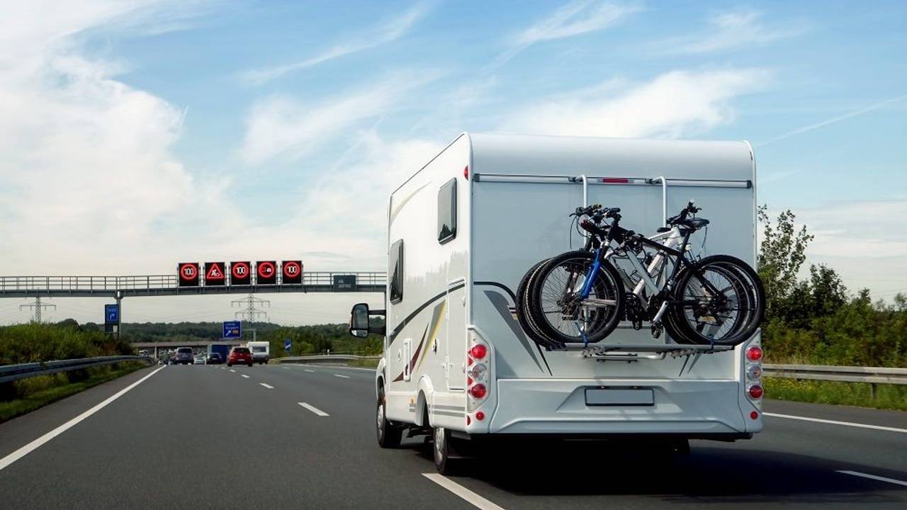 Hier zu sehen: Ein Wohnmobil, auf dem mehrere Fahrräder befestigt sind, fährt auf der Autobahn.
