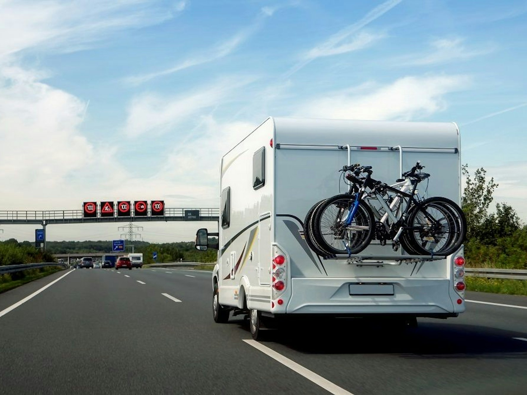 Hier zu sehen: Ein Wohnmobil, auf dem mehrere Fahrräder befestigt sind, fährt auf der Autobahn.
