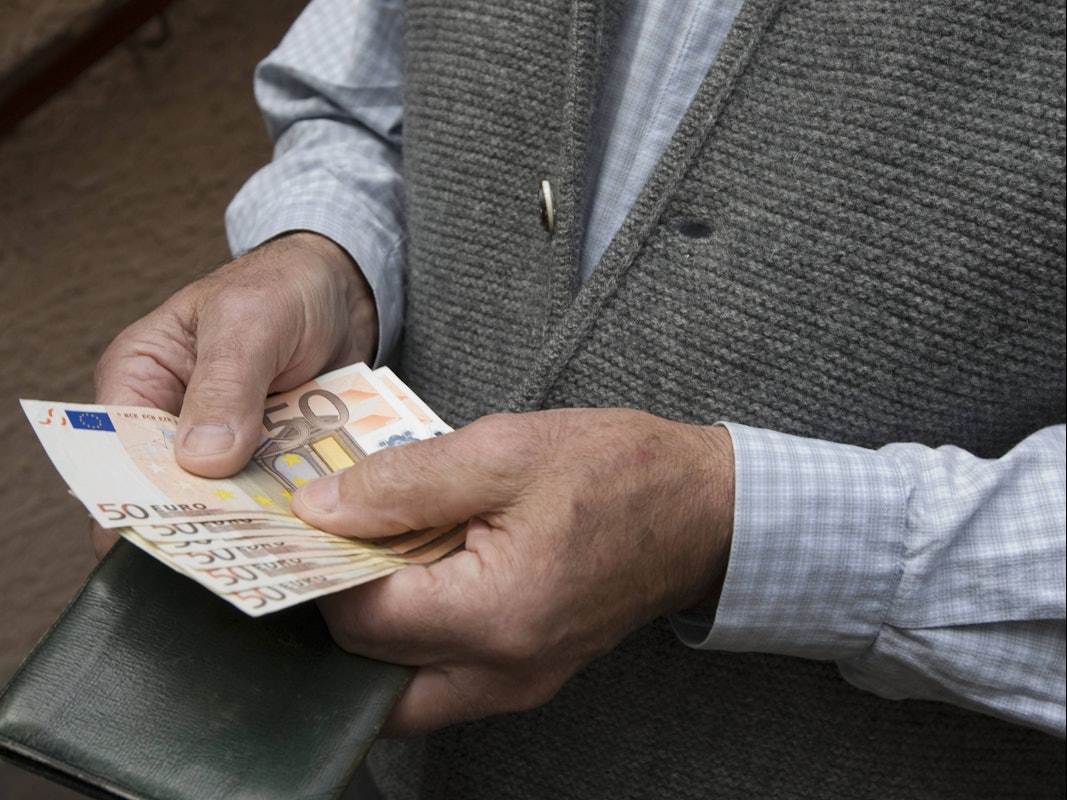 Ein Senior hält mehrere 50-Euro Scheine in den Händen.