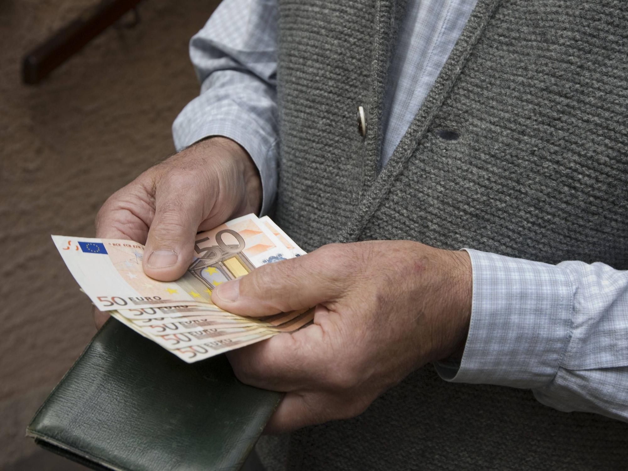 Ein Senior hält mehrere 50-Euro Scheine in den Händen.