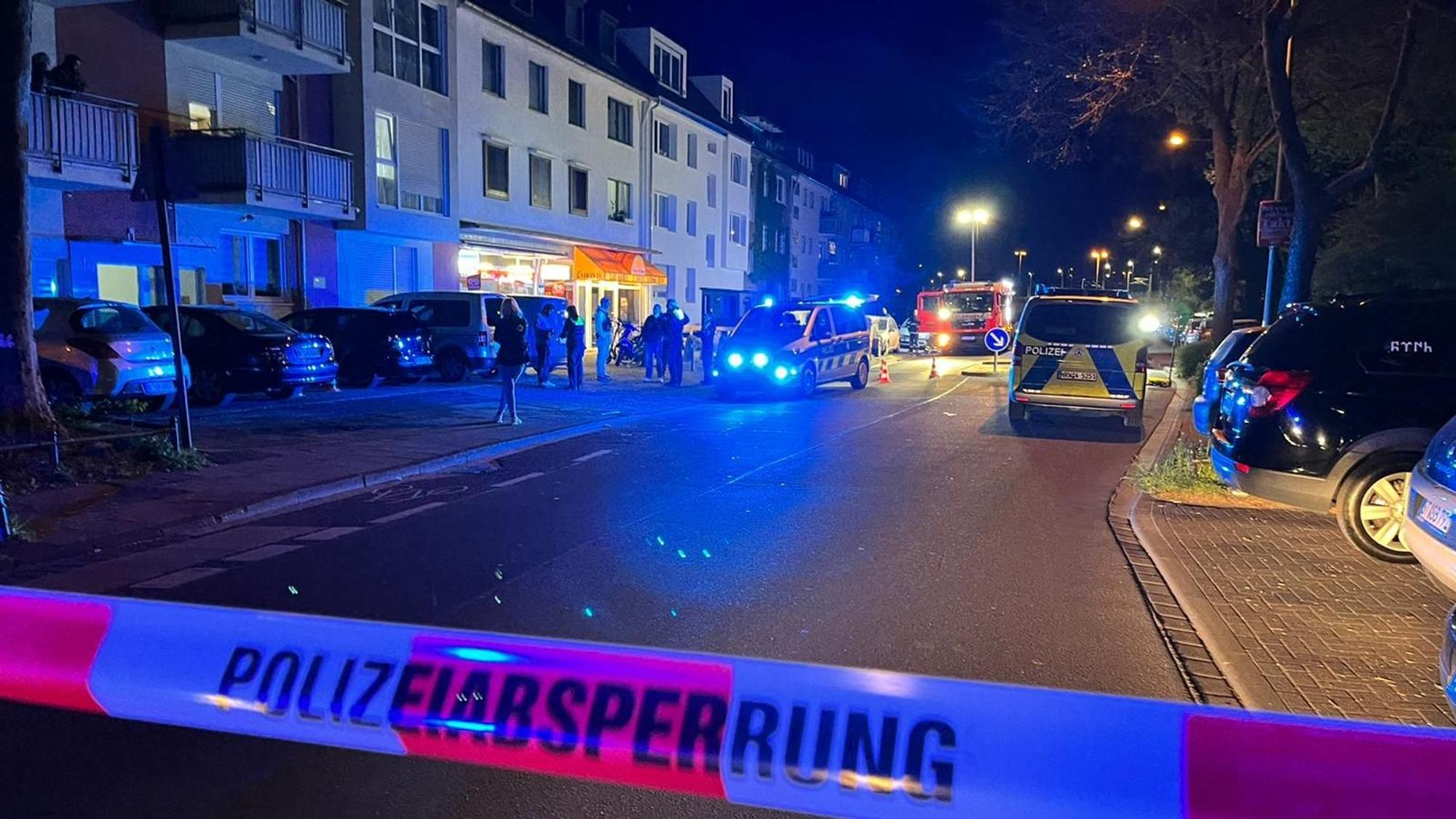 Eine Straße ist mit Flatterband der Polizei abgesperrt. Auf der Straße stehen mehrere Einsatzfahrzeuge vor einem Kiosk.