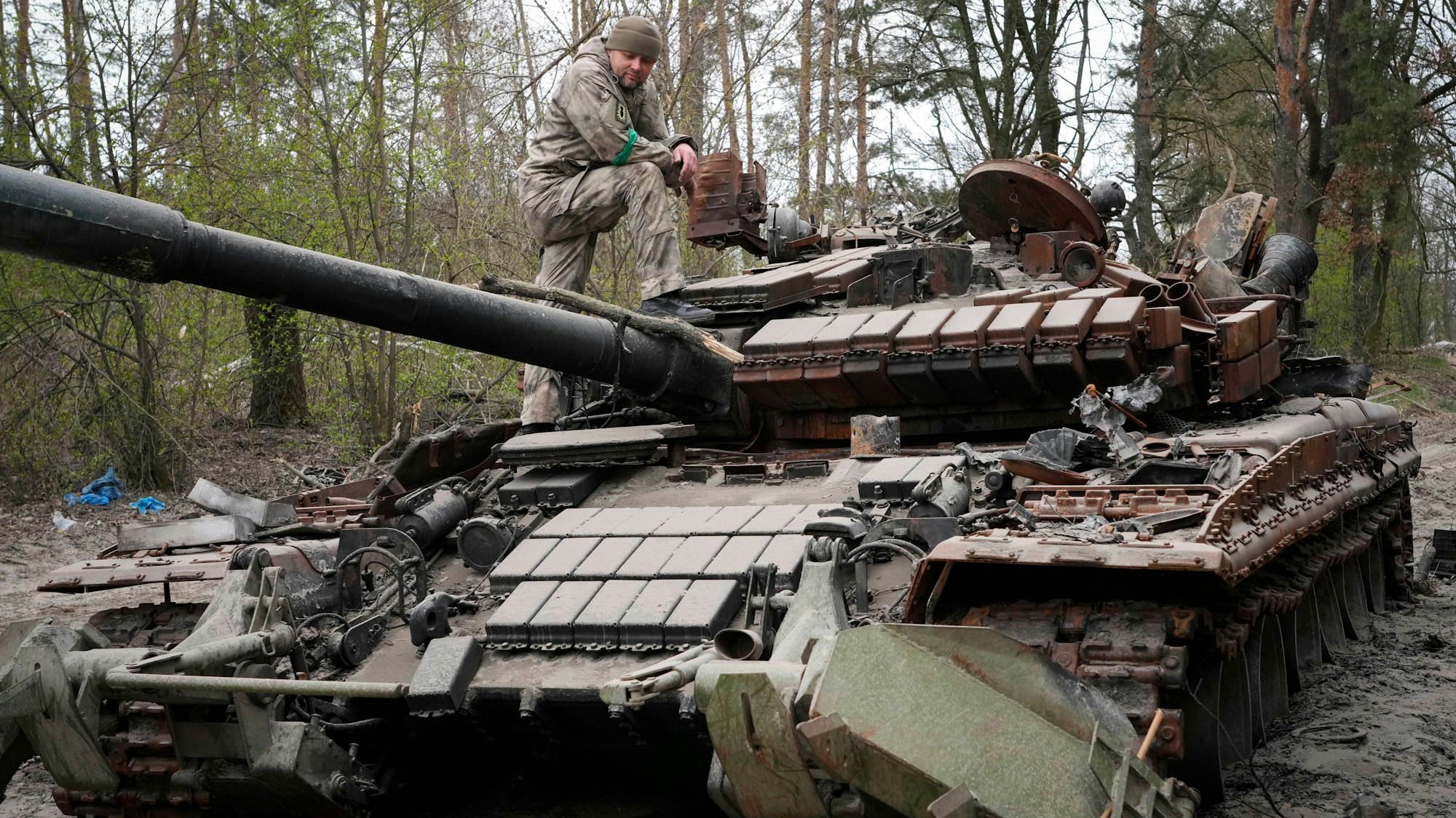 Ein ukrainischer Soldat inspiziert am 19. April 2022 einen russischen Panzer.