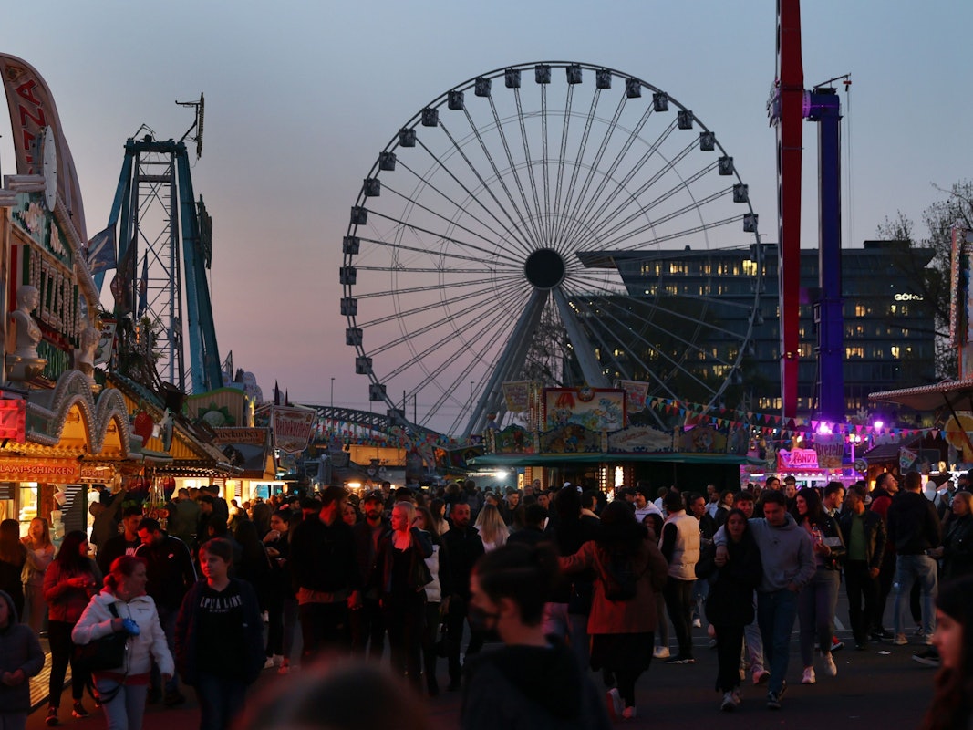Menschen gehen über die Deutzer Kirmes in Abendstimmung
