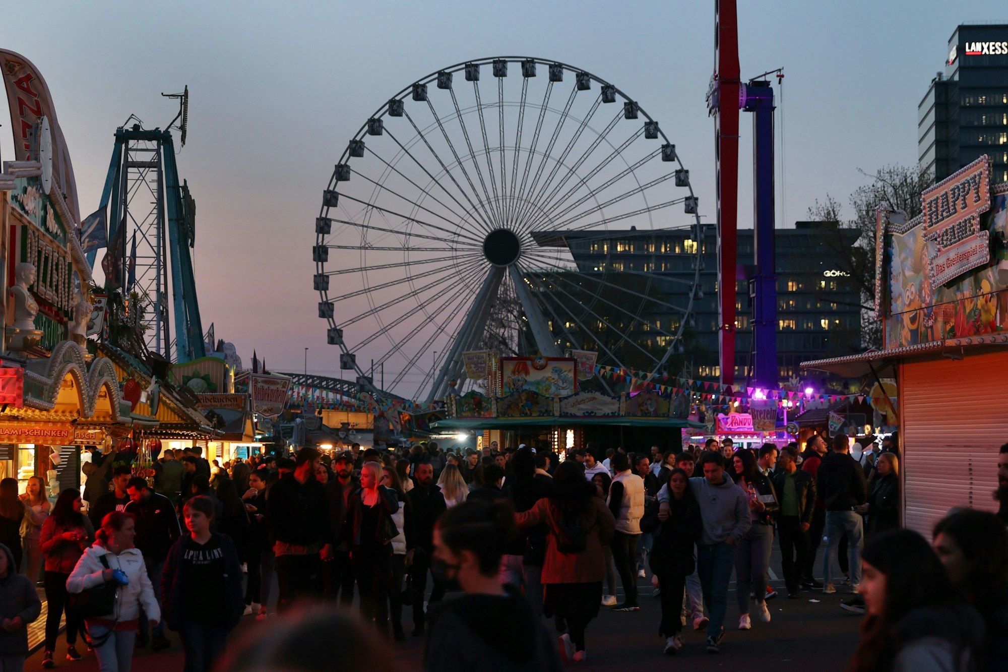 Menschen gehen über die Deutzer Kirmes in Abendstimmung
