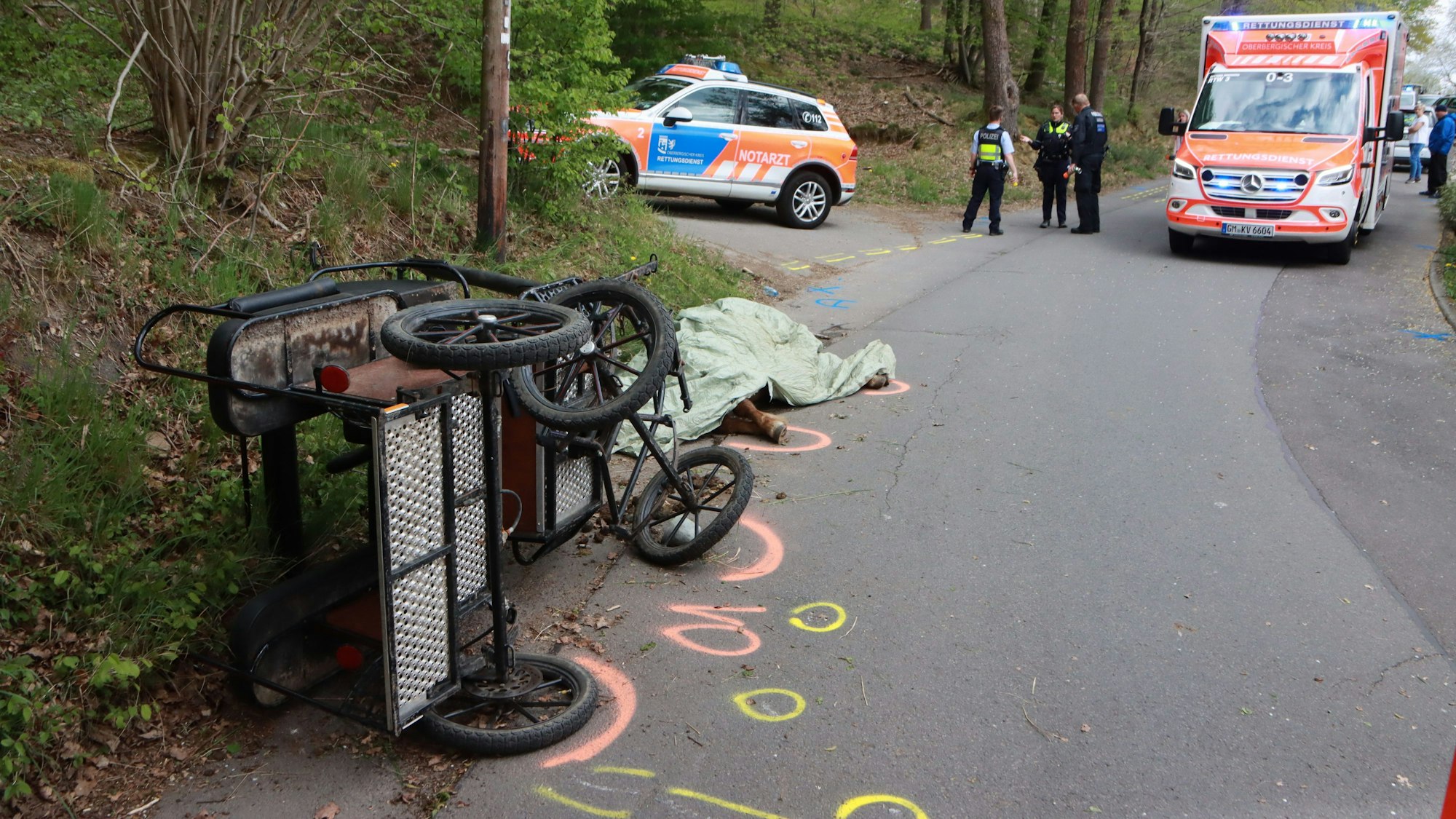 22.04.2022, Nordrhein-Westfalen, Wiehl: Nach dem Sturz einer Kutsche hat die Polizei die Unfallstelle markiert. Bei dem Unfall wurde ein Mädchen lebensgefährlich verletzt. Ein Pferd starb. Foto: Berthold Stamm/dpa +++ dpa-Bildfunk +++
