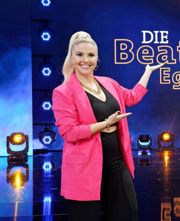 Beatrice Egli zeigt auf das neue Logo ihrer Schlagershow „Die Beatrice Egli Show“.