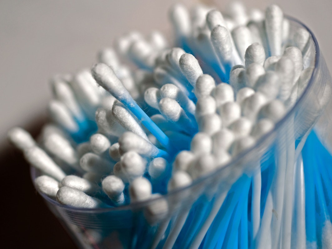 Wattestäbchen stehen in einem Glasbehälter.