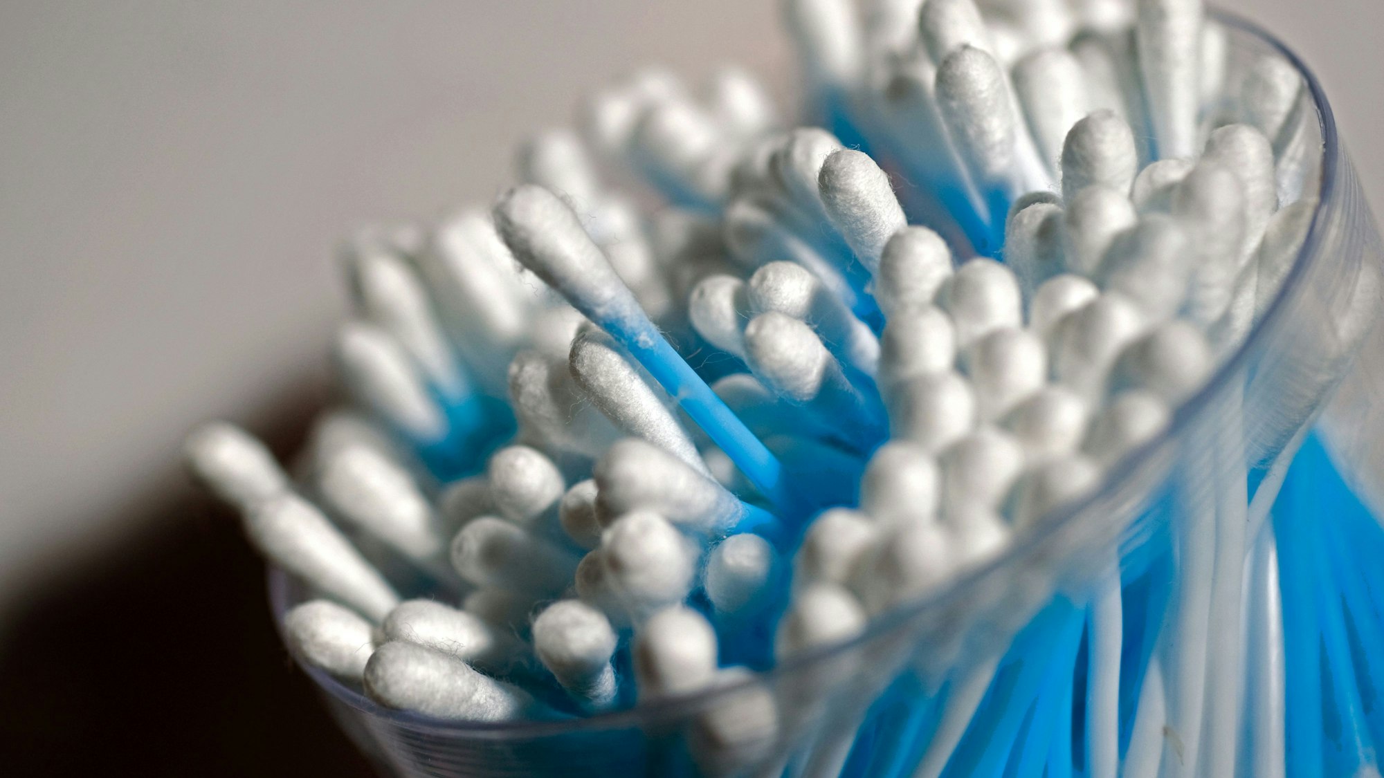 Wattestäbchen stehen in einem Glasbehälter.