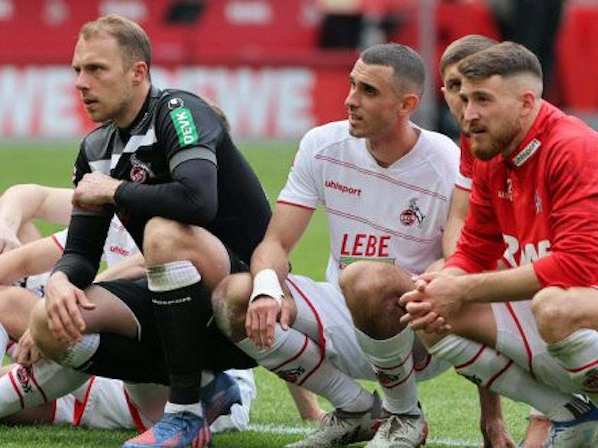 Marvin Schwäbe (l.) kniet mit Ellyess Skhiri, Jeff Chabot und Salih Özcan auf dem Boden.