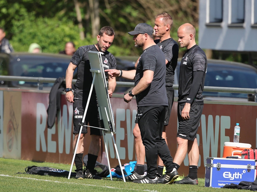 Das Trainerteam des 1. FC Köln studiert die Taktik-Tafel.