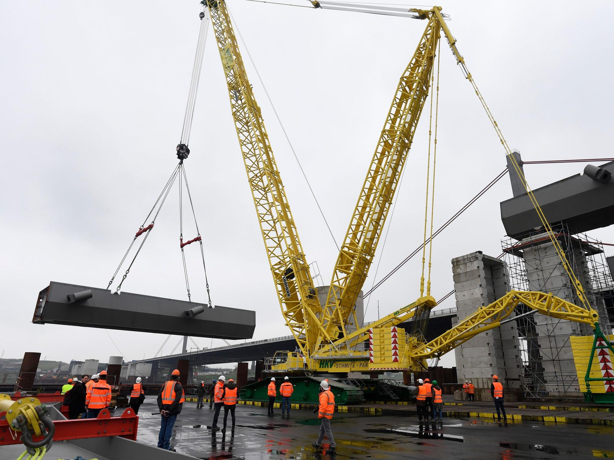 Ein Schwerlastkran hebt ein Stahl-Brückenteil zur A1-Autobahnbrücke (Hintergrund) bei Leverkusen.