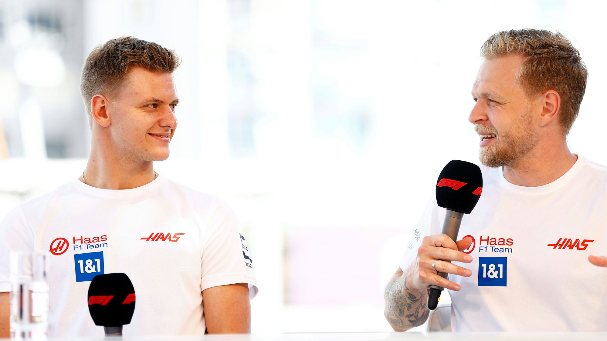 Mick Schumacher (links) und Kevin Magnussen schauen sich während eines Interviews an.