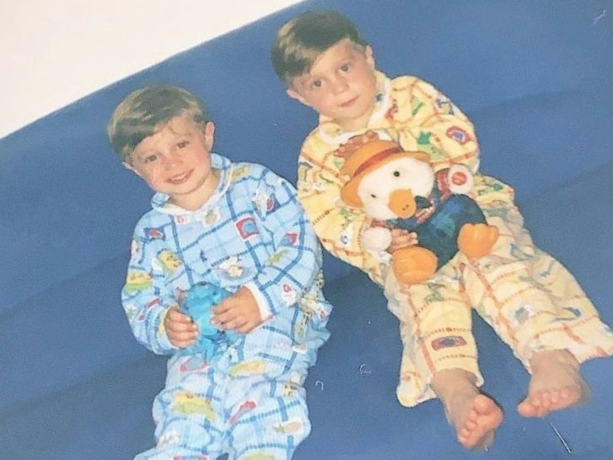 Roman und Nikita Kiselev sitzen als Kinder mit Kuscheltieren auf einem Sofa.