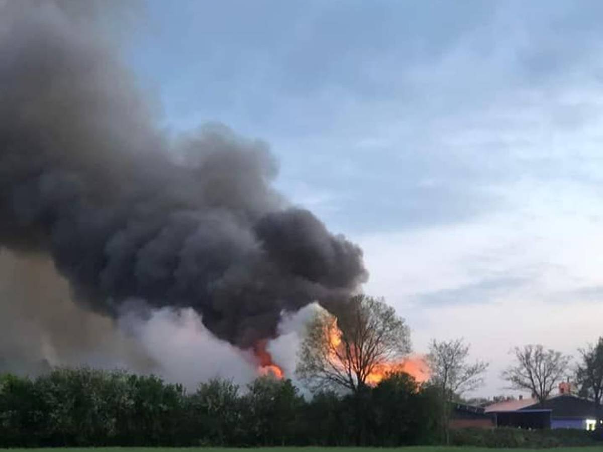 Von weitem sieht man hinter Bäumen lodernde Flammen und eine enorme Rauchsäule.