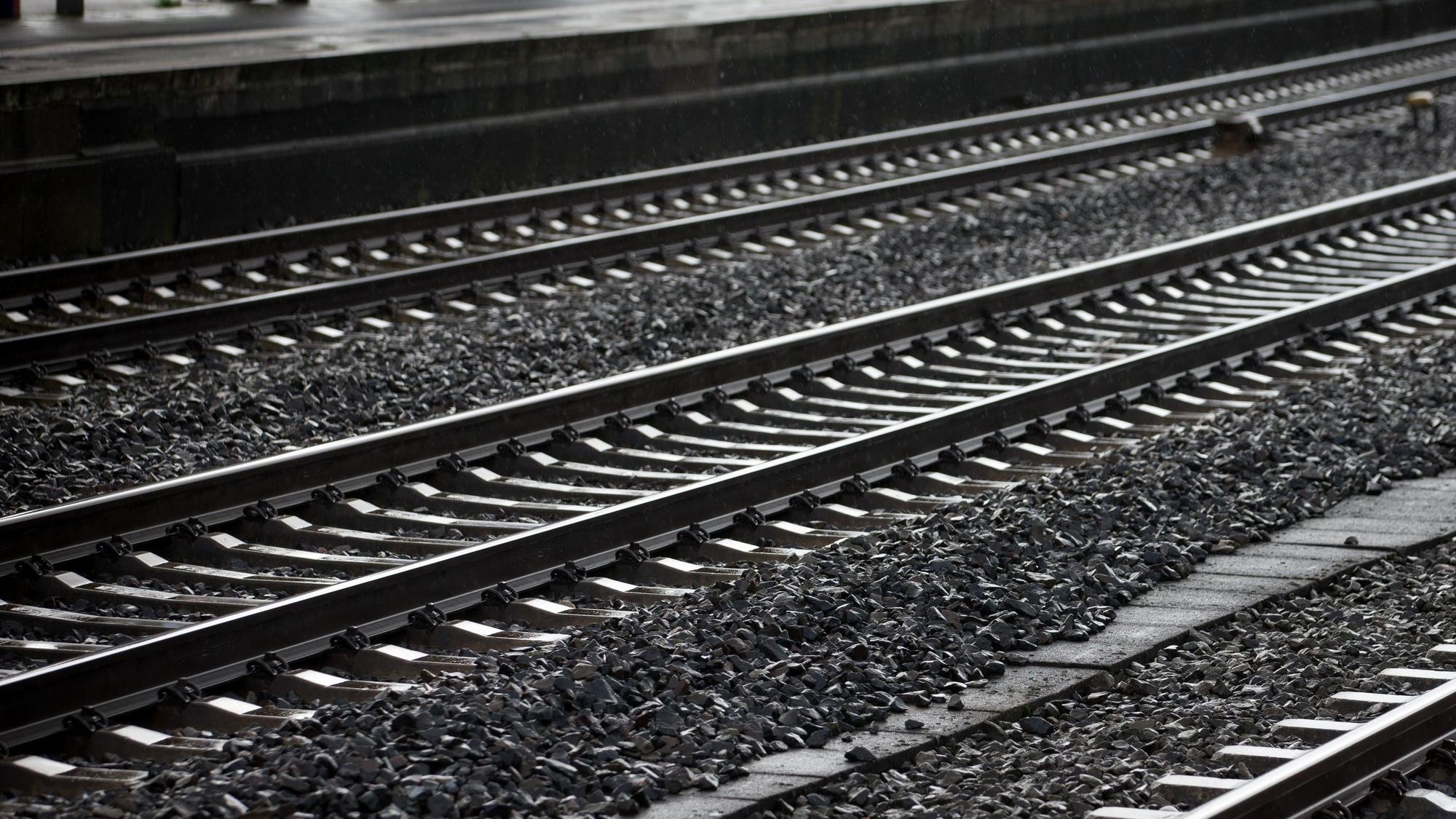 Es sind leere Bahngleise an einem Bahnhof zu sehen.