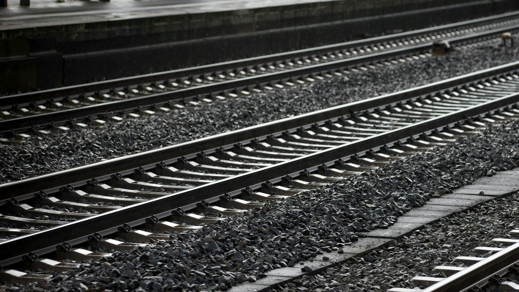 Es sind leere Bahngleise an einem Bahnhof zu sehen.