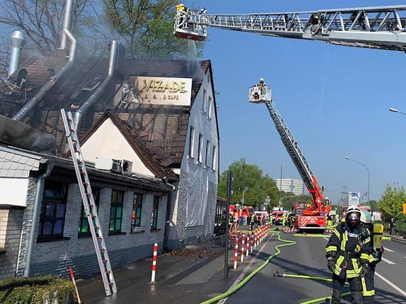 Die Feuerwehr löscht über eine Drehleiter ein brennendes Hausdach.