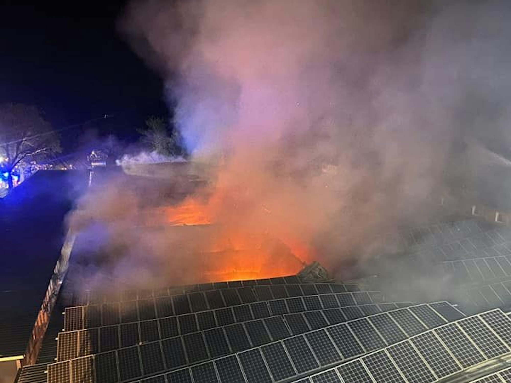 Flammen schlagen aus einem Dach, auf dem eine Photovoltaik-Anlage installiert ist.
