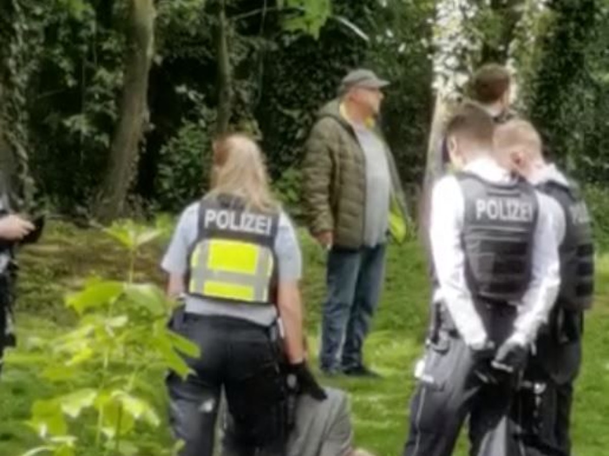 Eine Frau sitzt bei einem Polizeieinsatz mit Handschellen auf dem Boden.