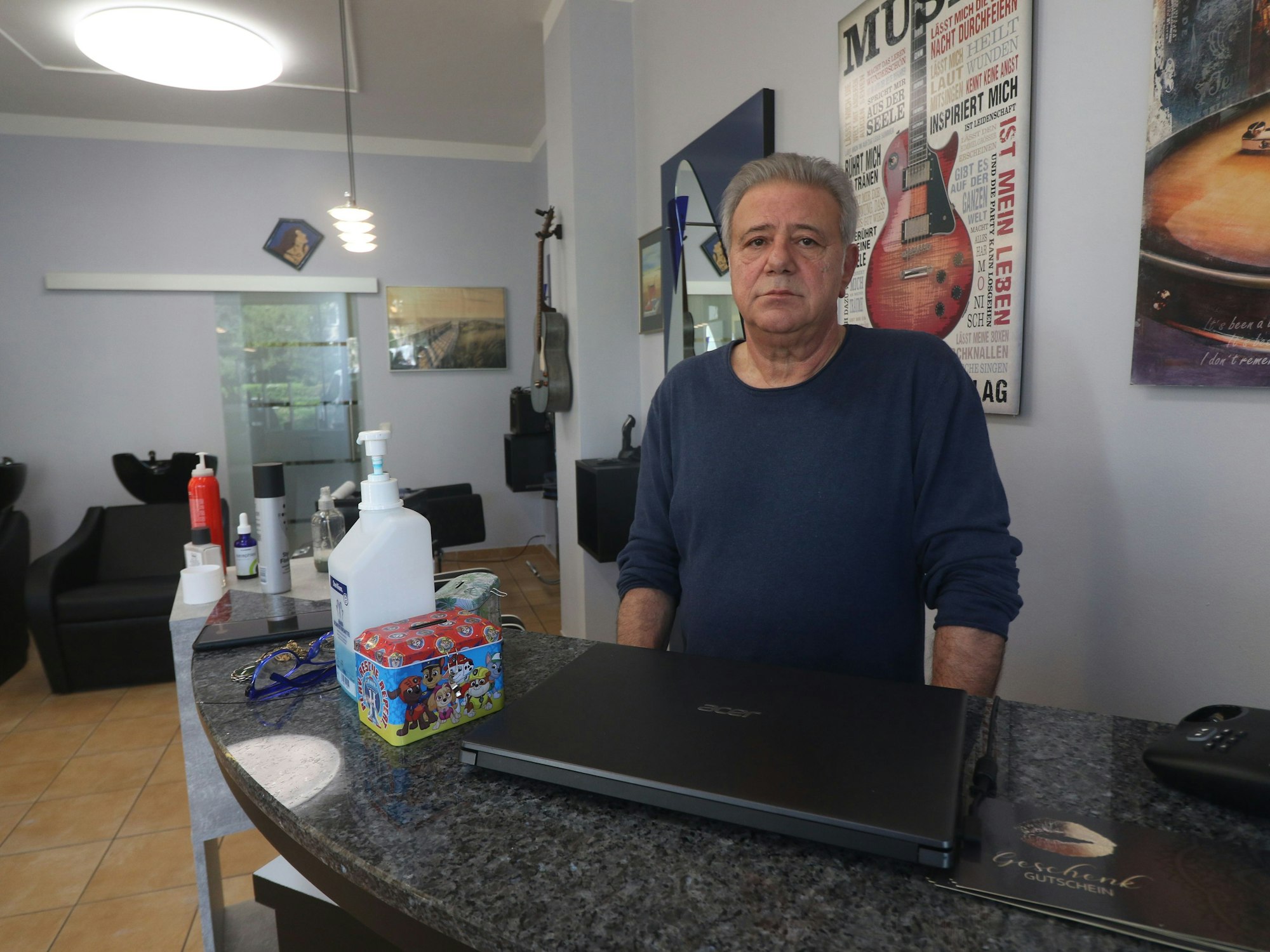 Ein Mann steht an einem Tresen eines Friseurgeschäfts.