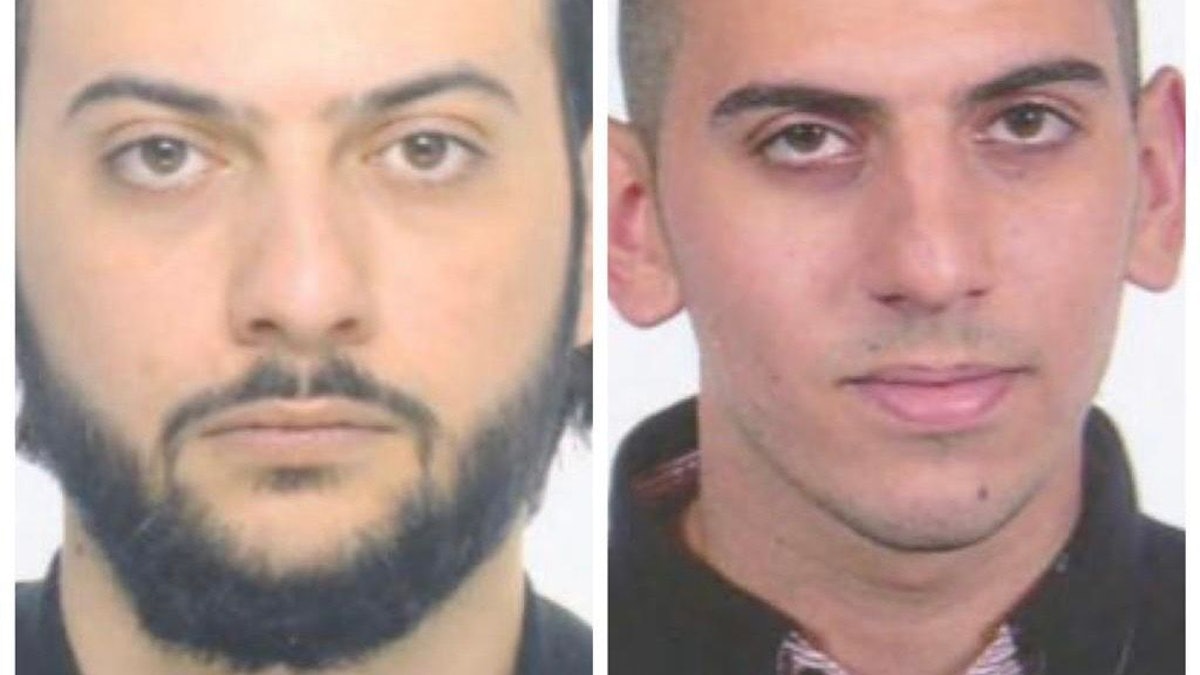 Zwei Männer schauen auf einem Fahndungsfoto in die Kamera.