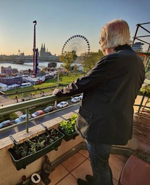 Ein Anwohner der Deutzer Werft steht auf dem Balkon und blickt auf die Osterkirmes.