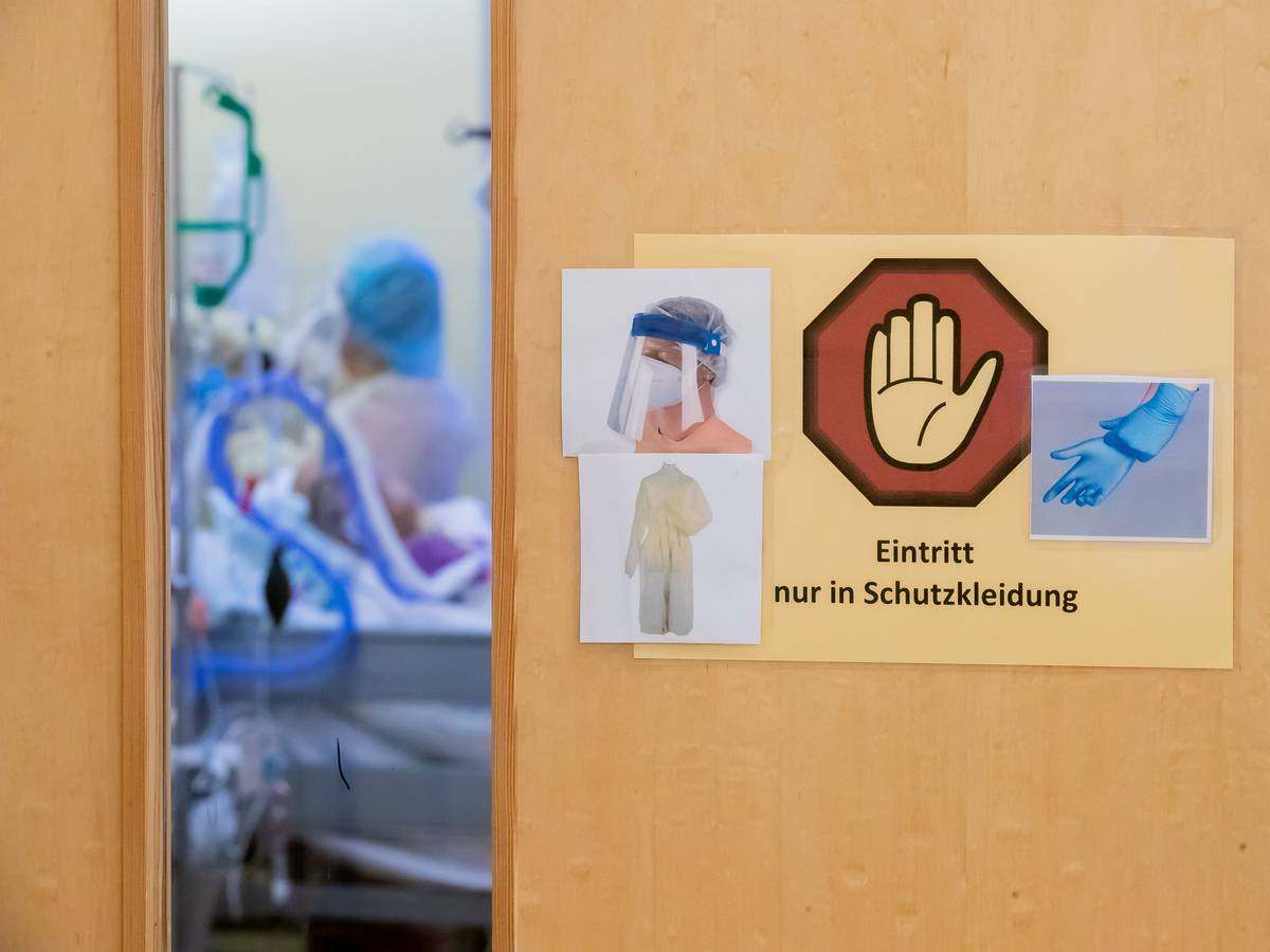 Ein Warnschild zum Tragen von Schutzkleidung hängt auf der Intensivstation des Gemeinschaftskrankenhauses Havelhöhe an der Tür eines Covid-19-Patientenzimmers.