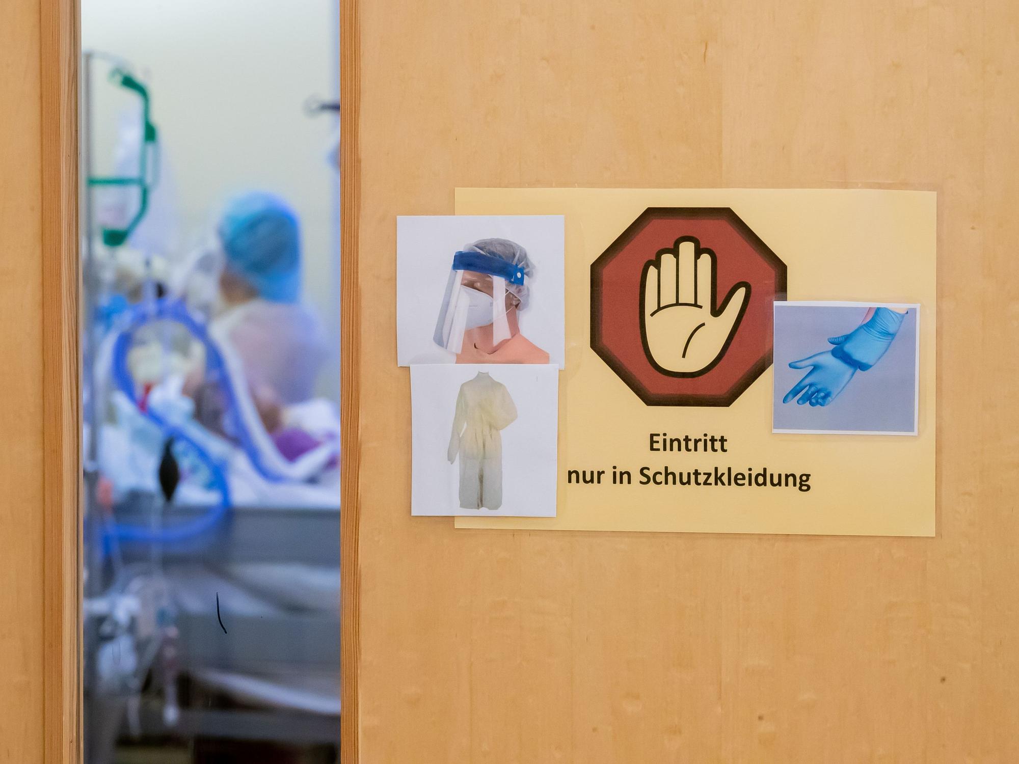 Ein Warnschild zum Tragen von Schutzkleidung hängt auf der Intensivstation des Gemeinschaftskrankenhauses Havelhöhe an der Tür eines Covid-19-Patientenzimmers.