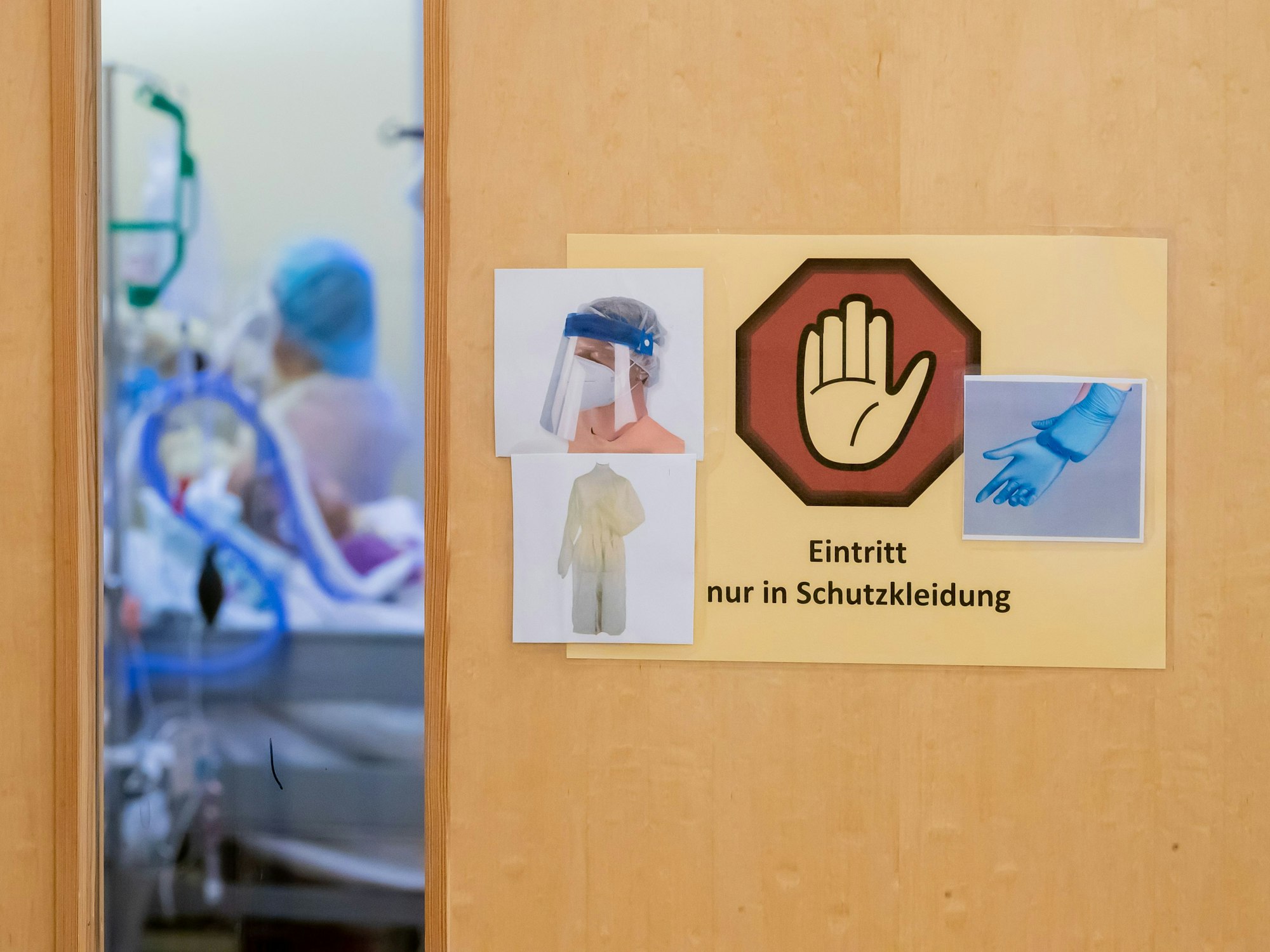Ein Warnschild zum Tragen von Schutzkleidung hängt auf der Intensivstation des Gemeinschaftskrankenhauses Havelhöhe an der Tür eines Covid-19-Patientenzimmers.